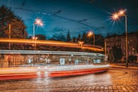 夜晚，电车在鹅卵石街道上行驶，灯光照亮了充满活力的城市场景