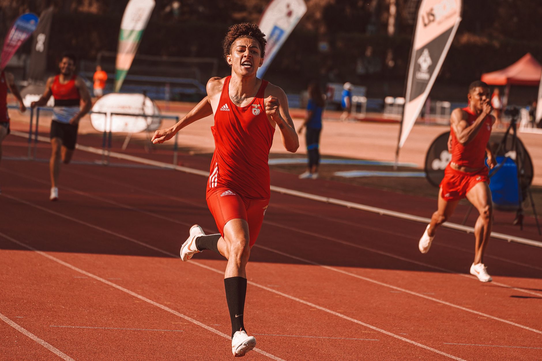 Amy Hunt 100 metre yarışını kazandıktan sonra sevinçle kollarını kaldırıyor