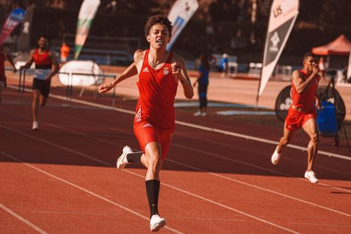 Free Determined young male athlete sprinting towards the finish line during a track and field race. Stock Photo
