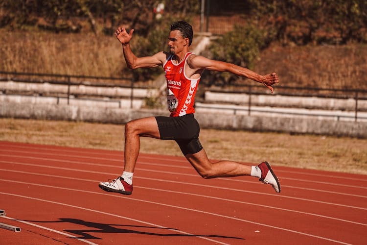 Athlete In Uniform Running On Stadium