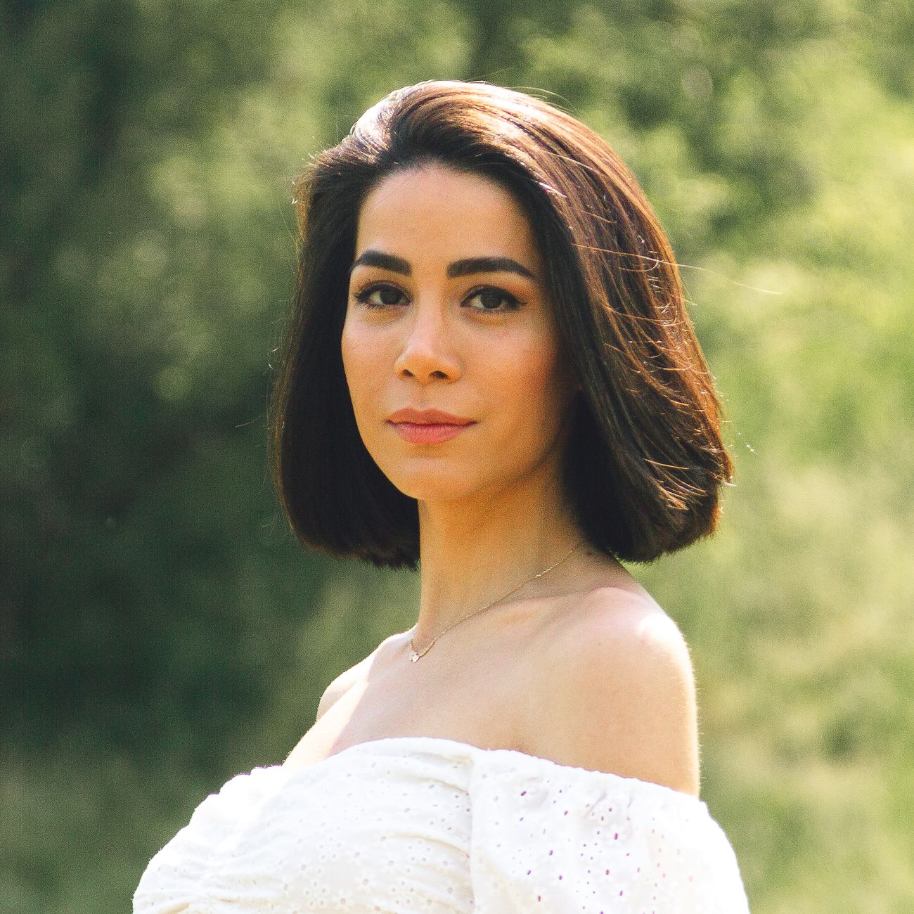 Portrait of an elegant woman with short hair in a natural outdoor setting.