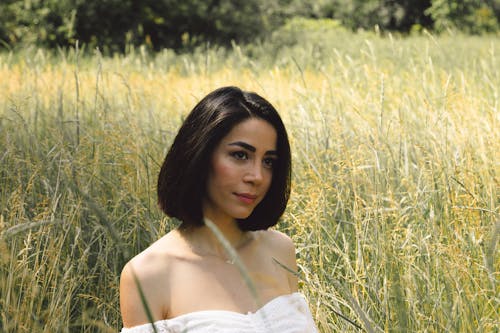 Woman in White Off Shoulder Shirt Standing on Green Grass Field