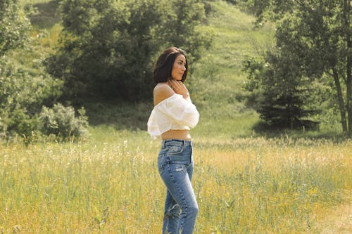 A Woman Wearing Off Shoulder Blouse and Denim Jeans