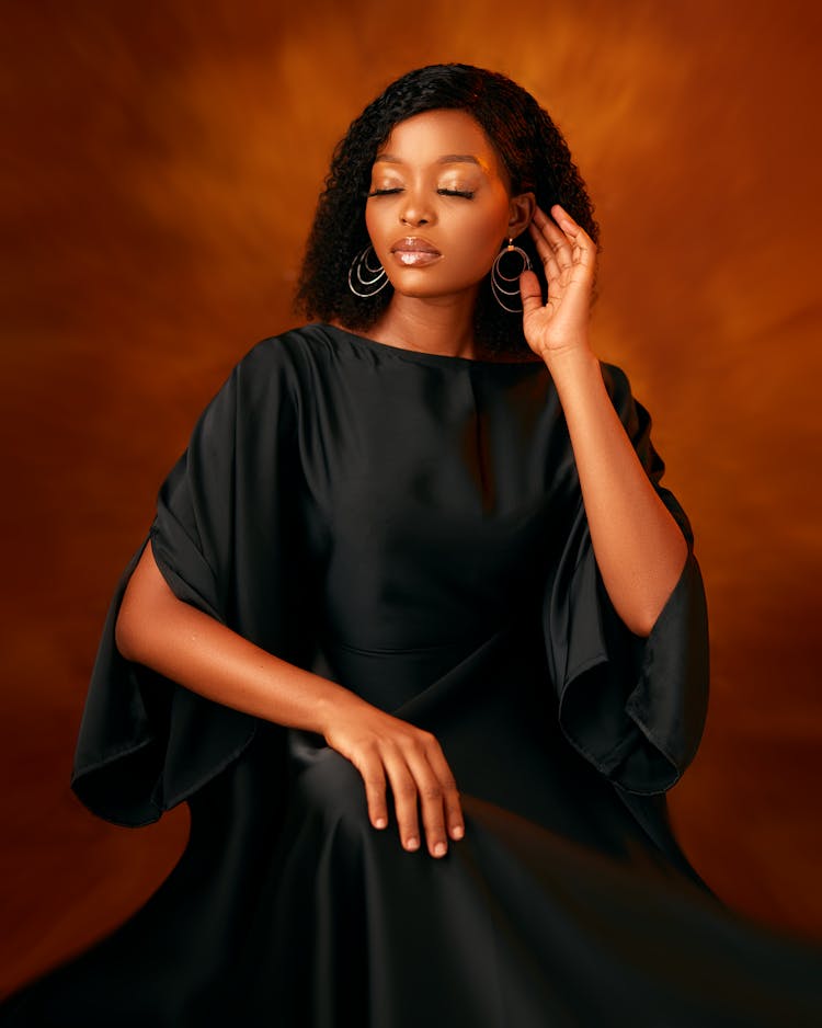 African American Beauty Sitting In Loose Black Dress