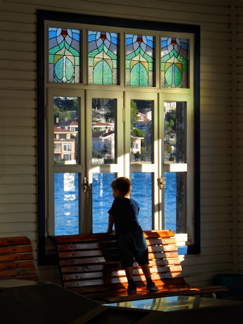 Kid standing on a Bench looking through a Window 