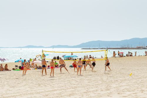 Free People enjoying a lively beach volleyball game under the summer sun in Spain. Stock Photo