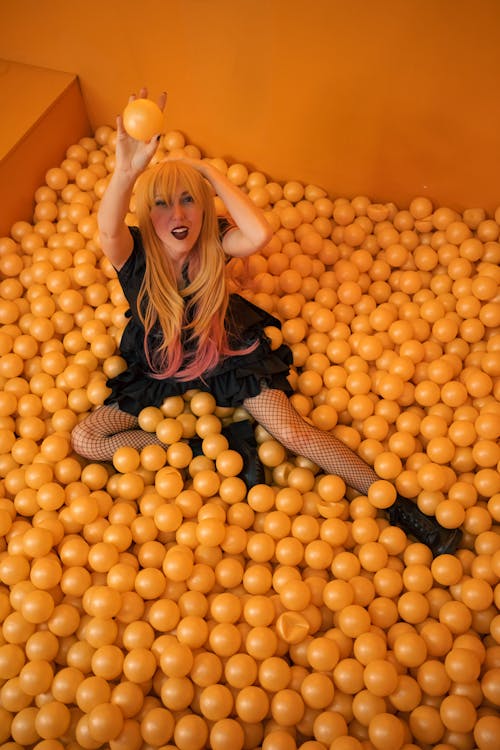 Girl Sitting amidst Orange Plastic Balls