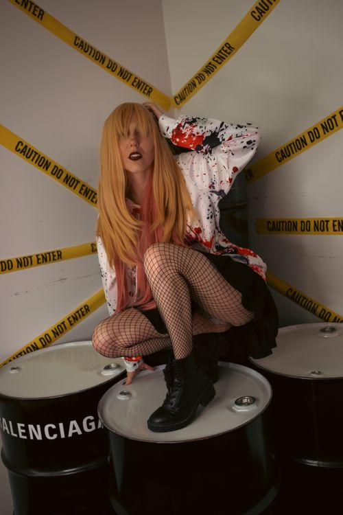 Free Fashion model sitting on barrels with 'Caution' tape, showcasing edgy style. Stock Photo