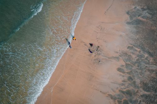 Free Drone capture of beach shoreline with waves and people enjoying the summer outdoors. Stock Photo