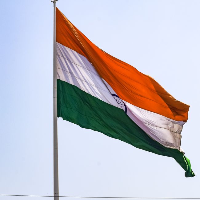 Indian national flag waving prominently against a clear blue sky, symbolizing patriotism and national identity.