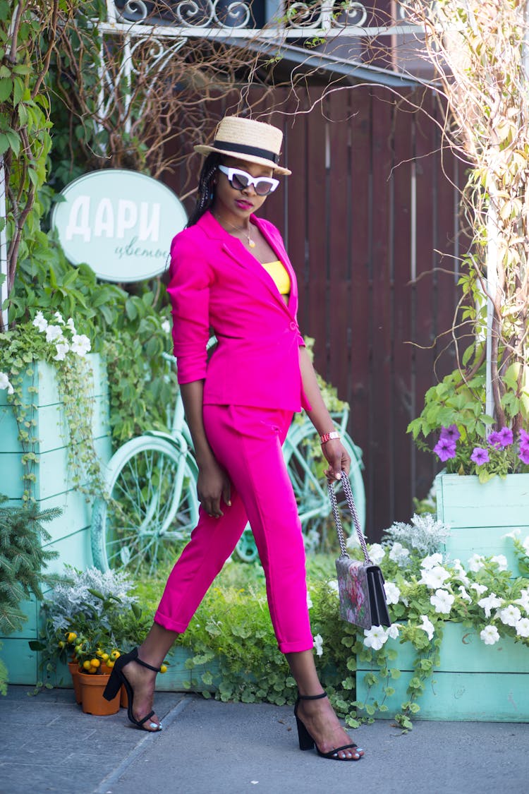 Woman In Pink Suit Walking Near Garden