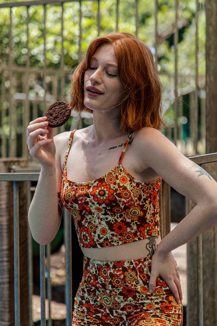 A Woman In Floral Outfit Eating A Cookie