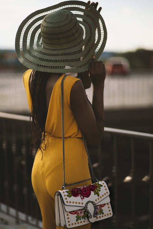 Woman Wearing Fascinator Hat and Yellow Jumpsuit