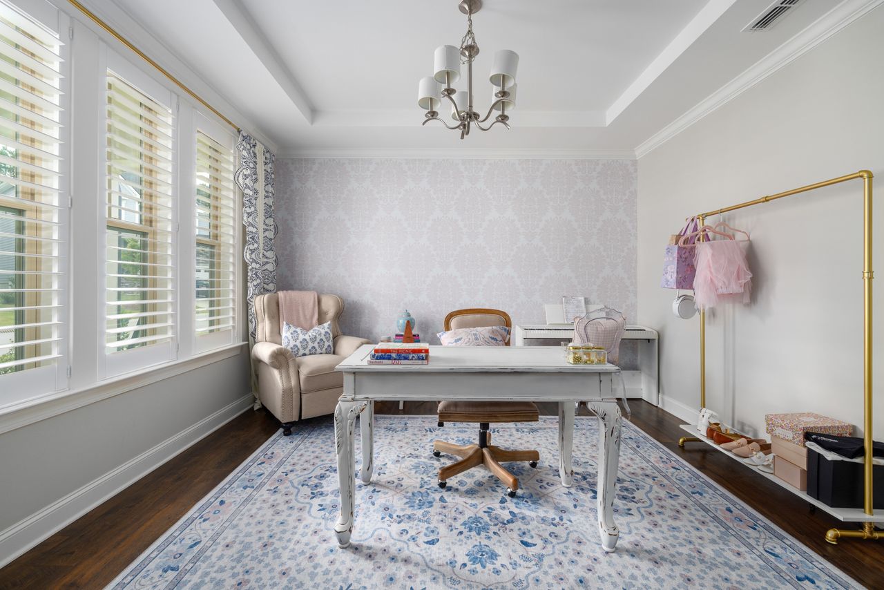 Elegant home office with a patterned feature wall behind the desk and a large floral rug