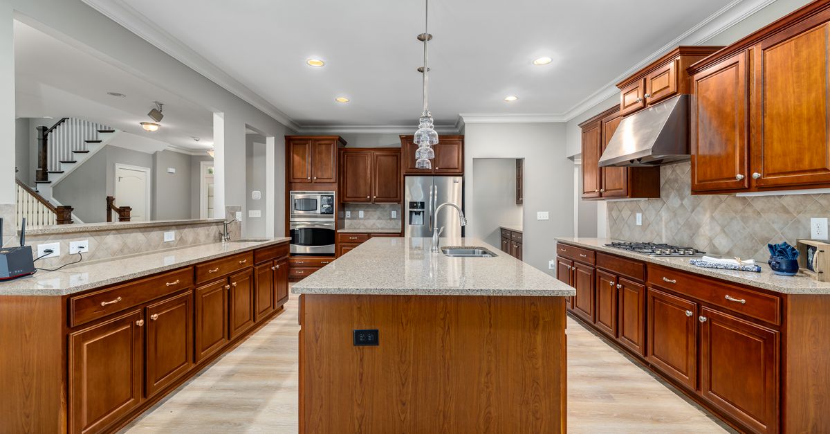 Spacious traditional kitchen with warm wood cabinets, granite island, and stainless steel appliances.