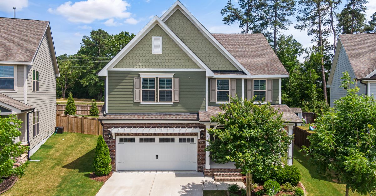 Aerial view of a modern green suburban home with a neatly landscaped front yard and garage in Wendell, NC.