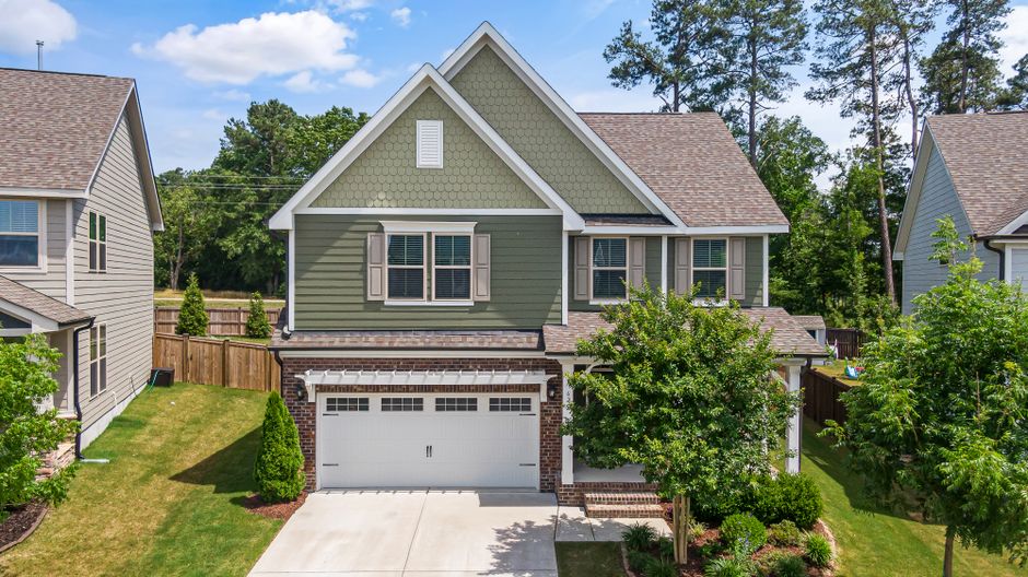 Aerial view of a modern green suburban home with a neatly landscaped front yard and garage in Wendell, NC.