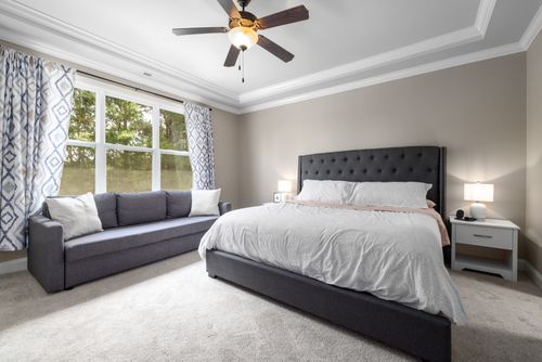 Free Minimalist bedroom featuring a king-sized bed, elegant furniture, and natural light through large windows. Stock Photo