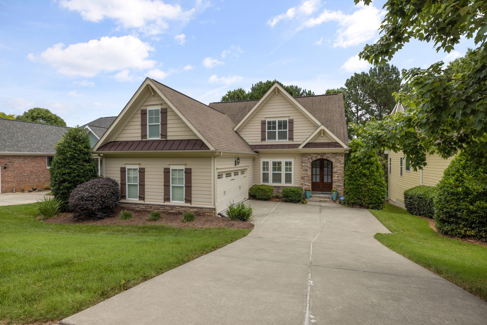 Two-story suburban home with tan siding, stone accents, and brown gabled rooflines, fronted by a driveway and mature trees, Winding Creek Estates, Naperville IL