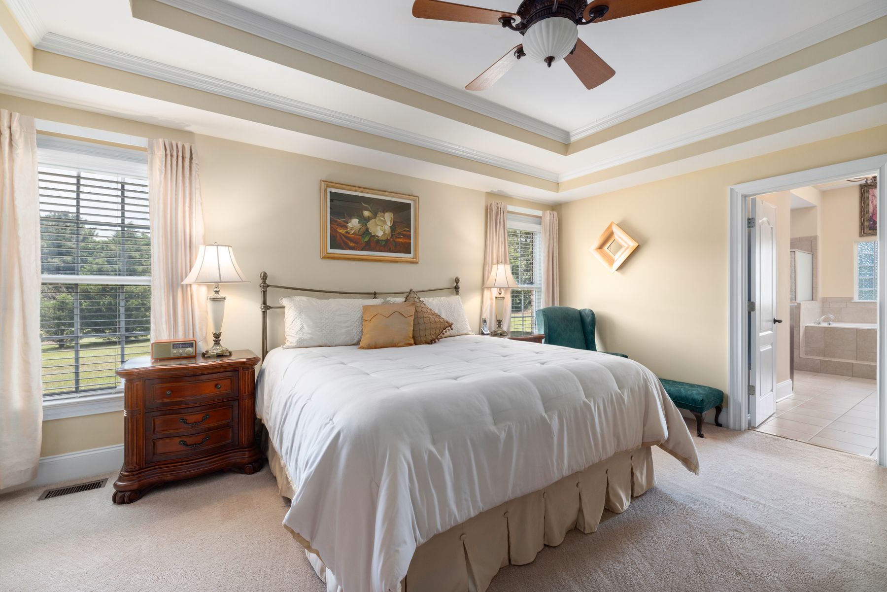 Refined warm bedroom with timber tables, upholstered headboard and layered cream bedding