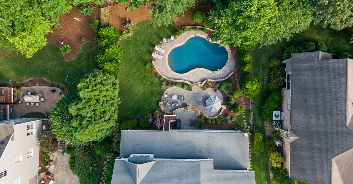 Aerial shot of a suburban backyard in Wake Forest, NC, featuring a swimming pool, garden, and seating area.
