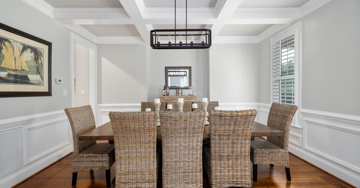 A beautifully designed dining room featuring wicker chairs, a wooden table, and minimalist decor.