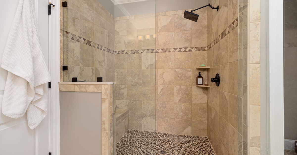 Elegant tiled shower interior with glass door and modern fixtures.