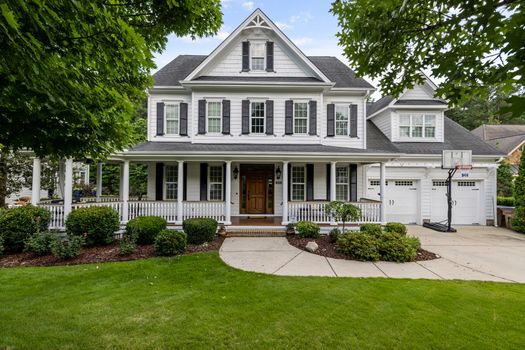 Charming suburban house with front porch, landscaping, and white facade.