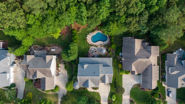 Aerial view of suburban neighborhood in Wake Forest, NC, showcasing lush green backyards and a swimming pool.