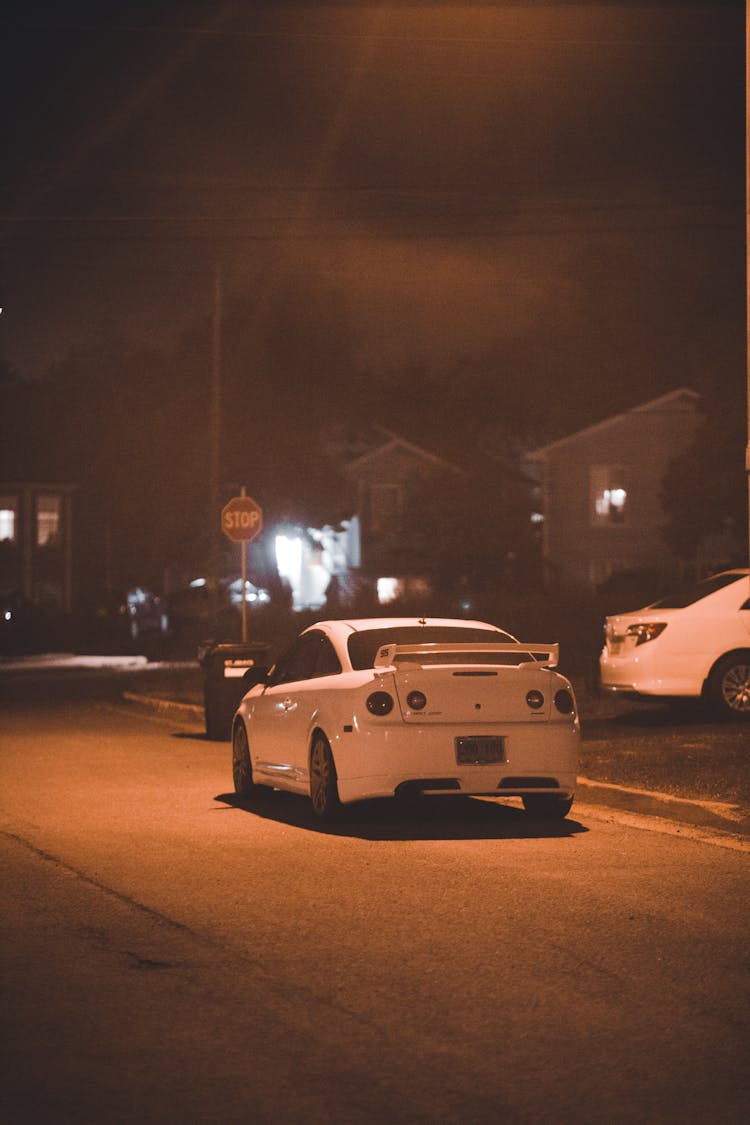 Back View Of A White Car On A Road At Night