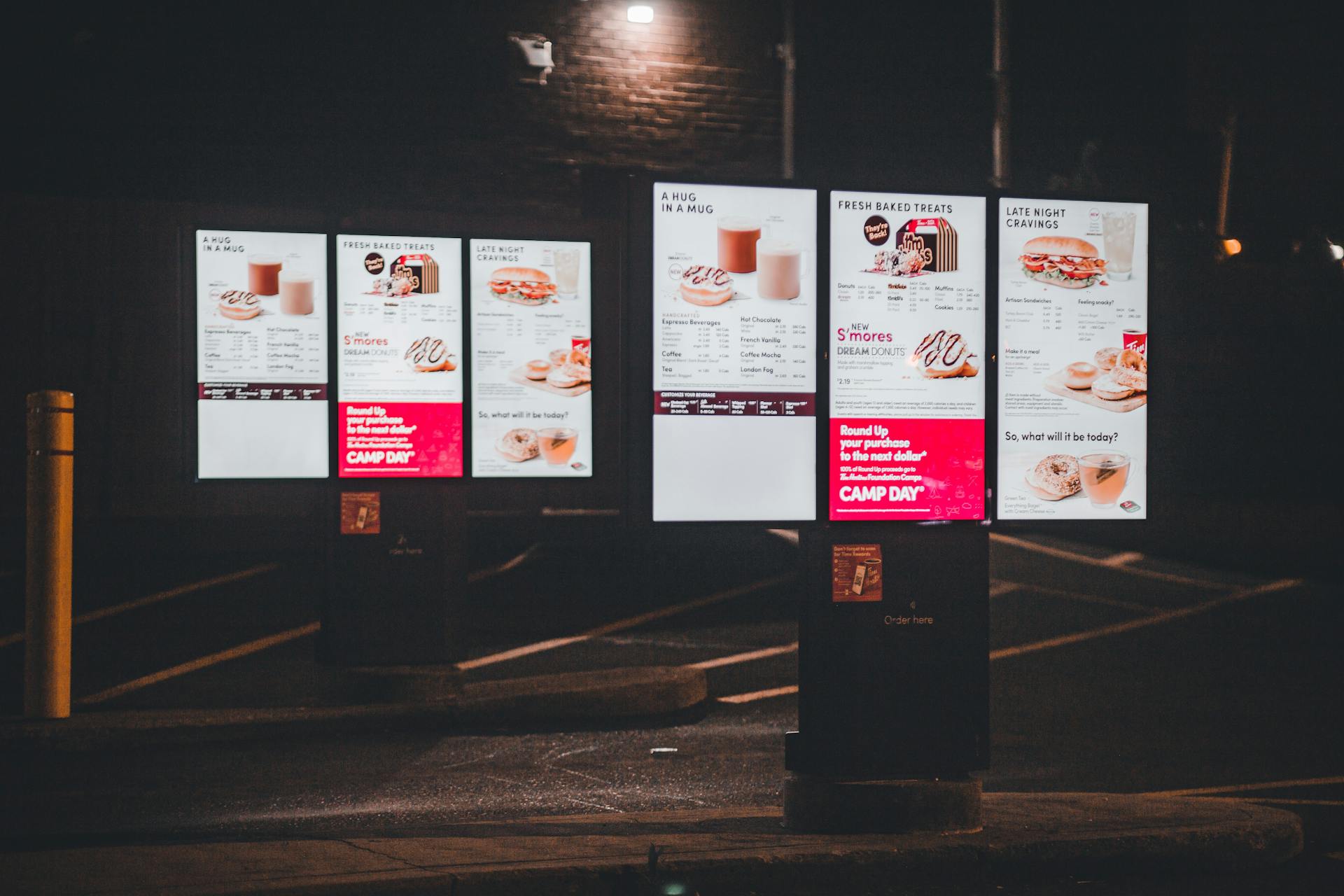 Nighttime view of an illuminated fast food drive-thru menu with digital display and clear copyspace.