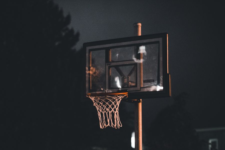 A basketball hoop lit up at night — photo by Erik Mclean on Pexels