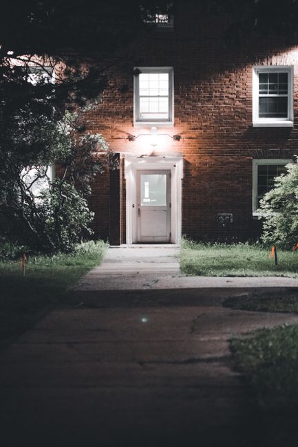 A lit entrance of a brick building at night, creating a moody urban atmosphere.