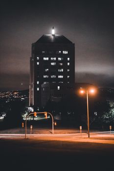 A high-rise building illuminated at night amidst an urban setting with street lights.