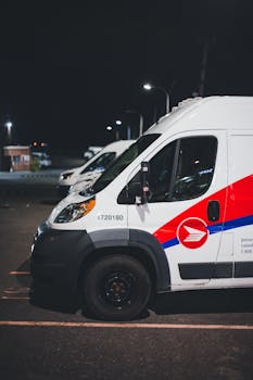 A row of Canadian postal delivery vans parked in a lot during nighttime.