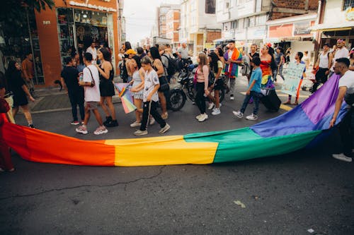 A Parade of People on the Street with a Rainbow Flag