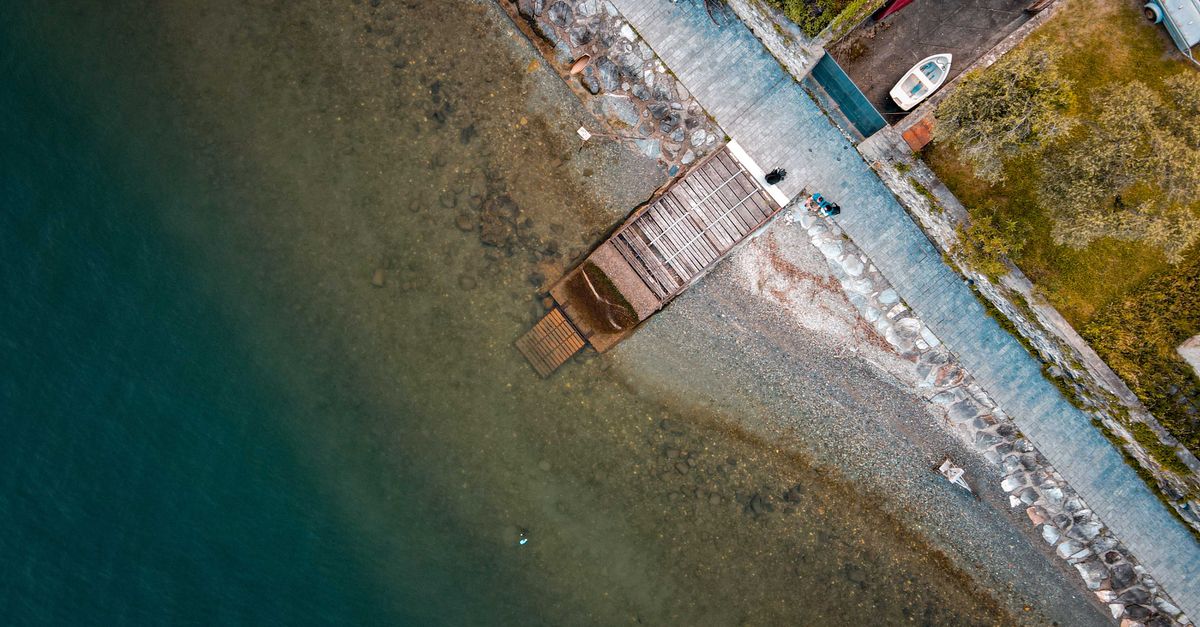 Aerial view of a serene coastal pier with a nearby boat and clear water.