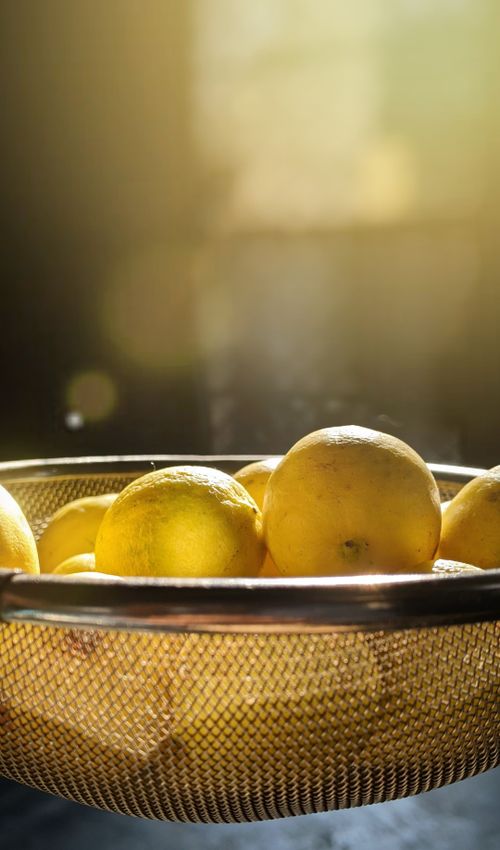 Free Close-up of fresh lemons in a strainer, bathed in warm sunlight, showcasing vibrant colors. Stock Photo