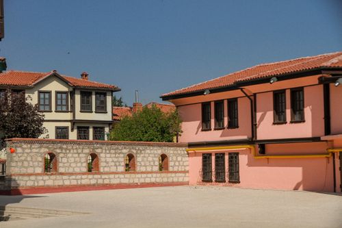 Free Colorful traditional houses with a classic stone wall under a clear blue sky. Stock Photo
