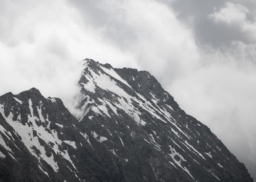 Free Majestic snow-covered mountains in Tirol, Austria under a dramatic cloudy sky. Stock Photo