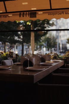 Cozy restaurant table outdoors with glassware and plates, perfect for dining in a serene setting.