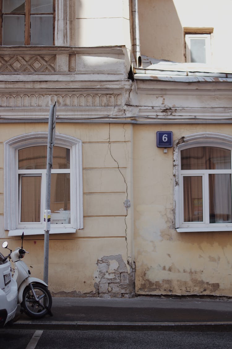 Motorbike Parked By A Weathered Yellow Townhouse