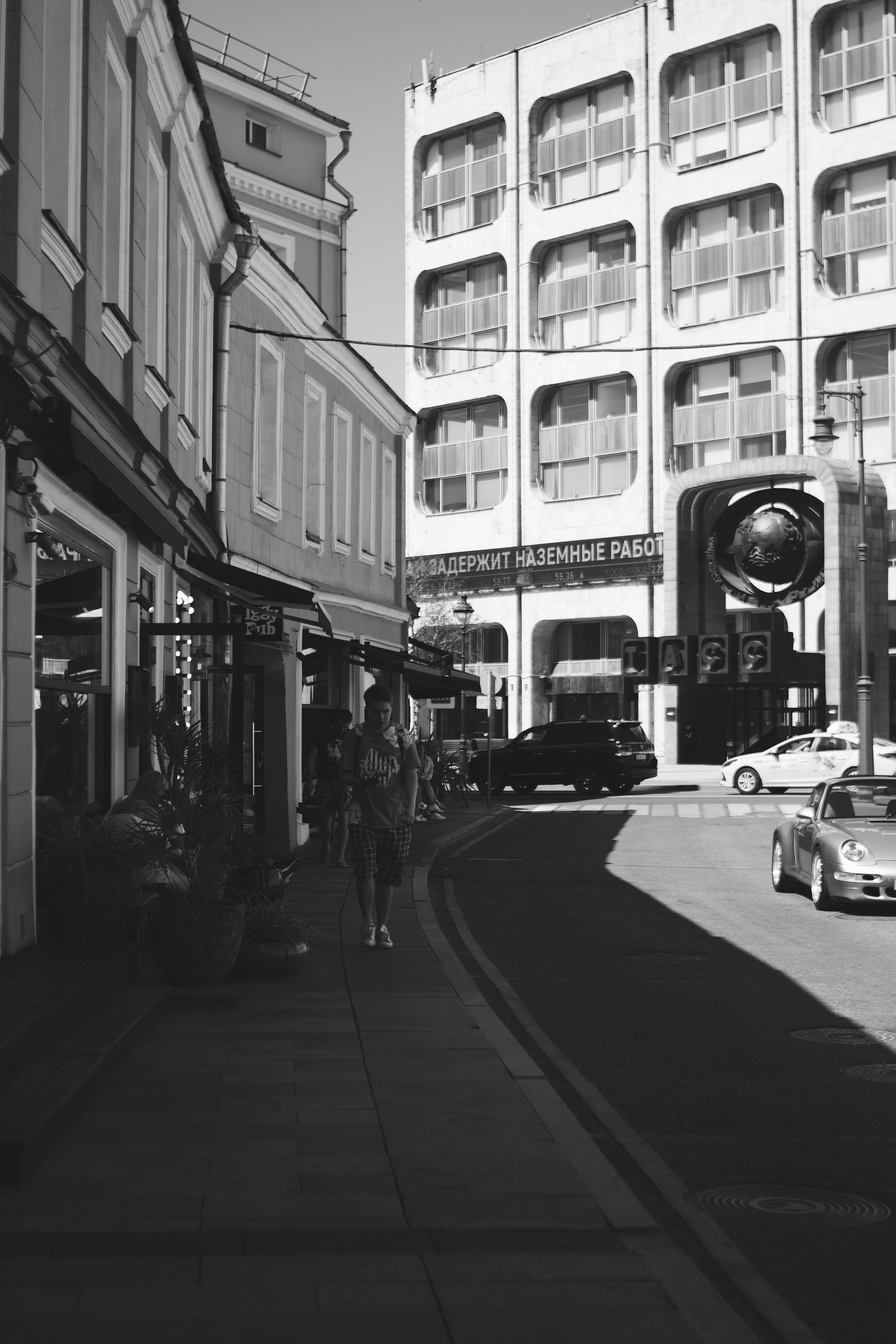 Free Black and white city street view showcasing urban architecture and pedestrians. Stock Photo