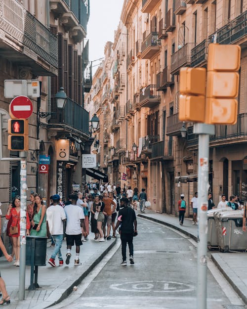 People Walking on the Street Between Buildings