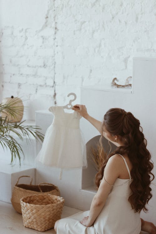 Free Pregnant Woman Holding and Looking at a Little Dress  Stock Photo