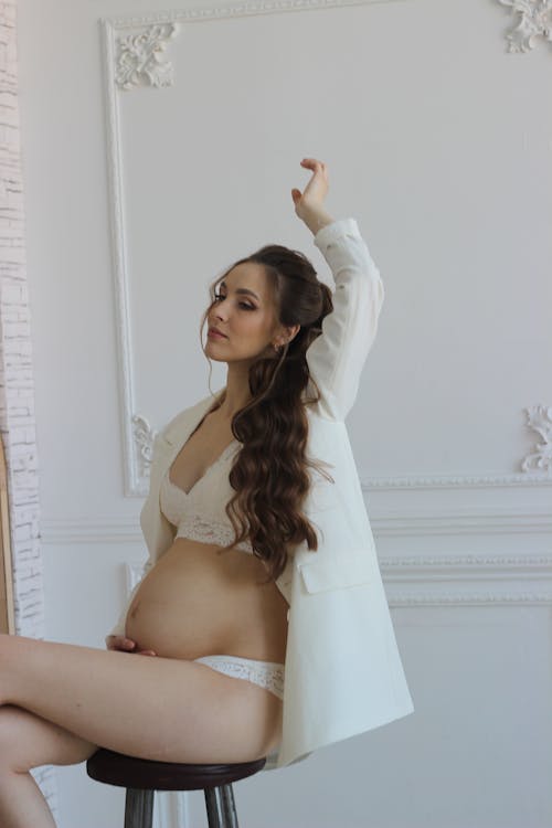 Happy pregnant woman in bra and panties holding stomach stock photo