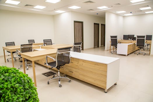 Spacious office interior with wooden desks and ergonomic chairs, perfect for a productive workday.