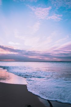 A tranquil beach scene at sunset showcasing gentle waves and pastel skies.