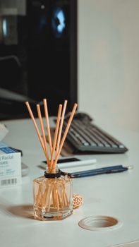 Stylish office desk with a reed diffuser, computer monitor, stationery, and subtle lighting, capturing an elegant workspace in Dubai.