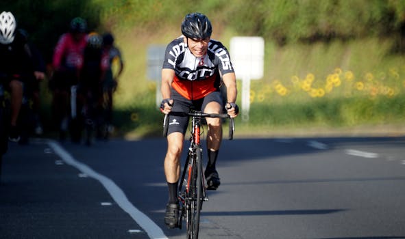 A cyclist competing in a road race with a focused expression on a sunny day.